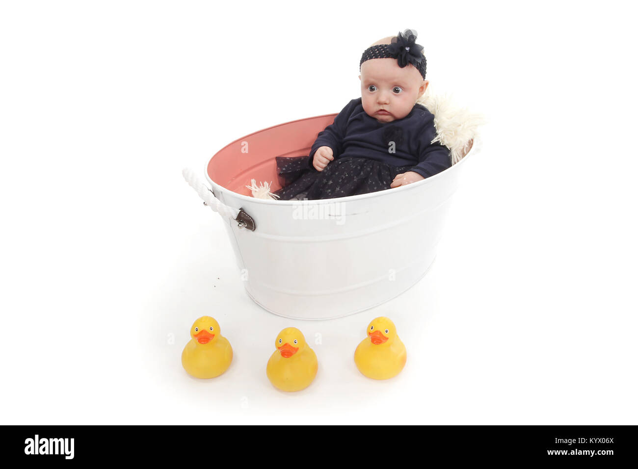 5 month old baby girl with in black dress sitting in a tin tub Stock Photo