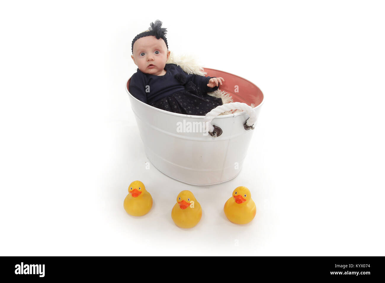 5 month old baby girl with in black dress sitting in a tin tub Stock Photo