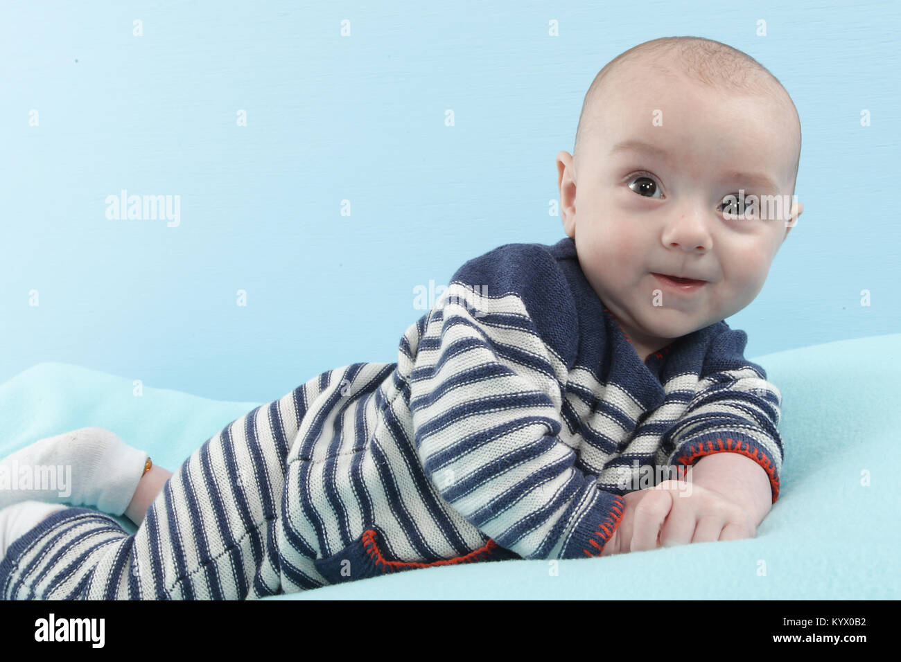 12 week old baby boy exploring on soft blue blanket Stock Photo