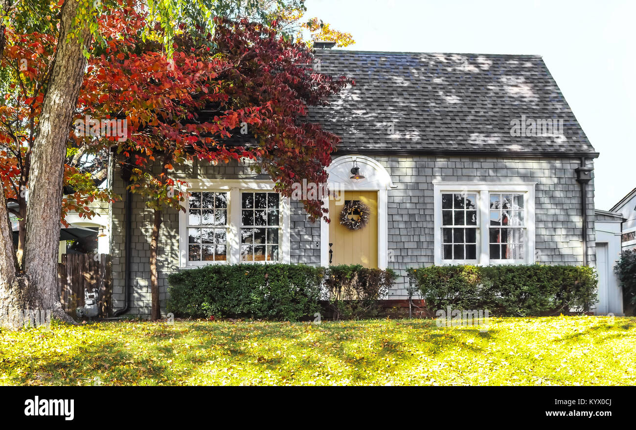 Beautiful grey wood shingle cottage with autumn trees and wreath on door Stock Photo