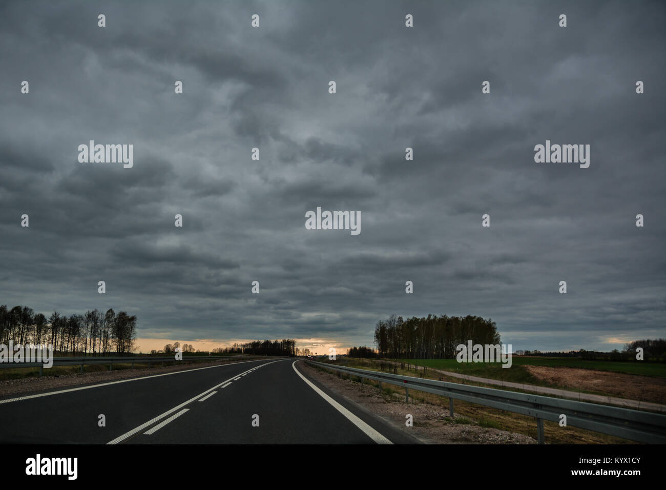 Empty asphalt road in bend on overcast spring day with light at the ...