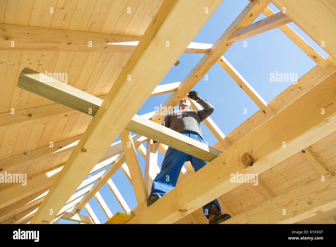 Builder at work with wooden roof construction. Stock Photo