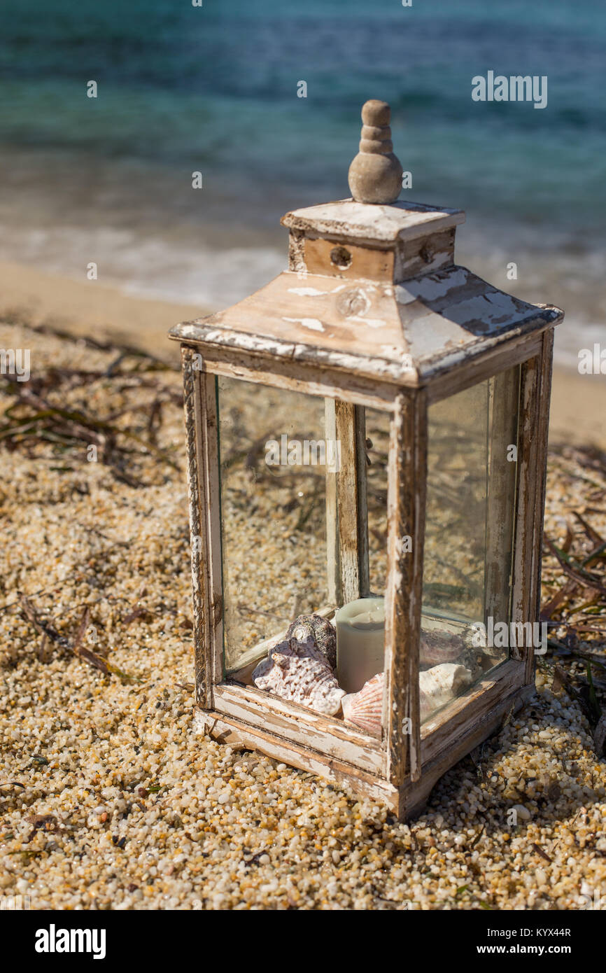 Wooden rustic lantern with gray candle and seashells inside at the beach  against the background of turquoise sea. Vertical composition Stock Photo -  Alamy