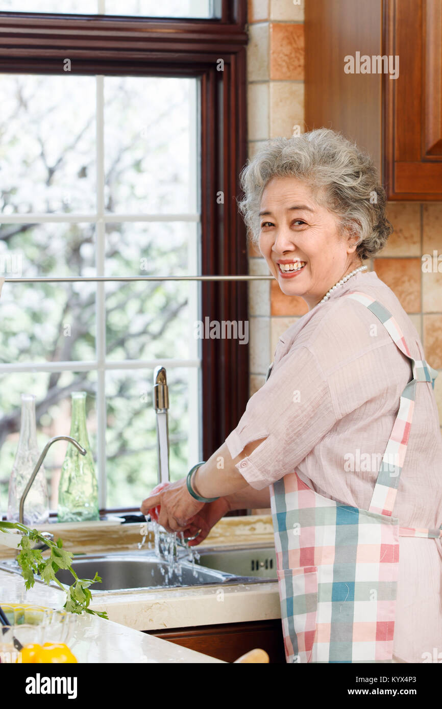 The old woman is washing vegetables in the kitchen Stock Photo