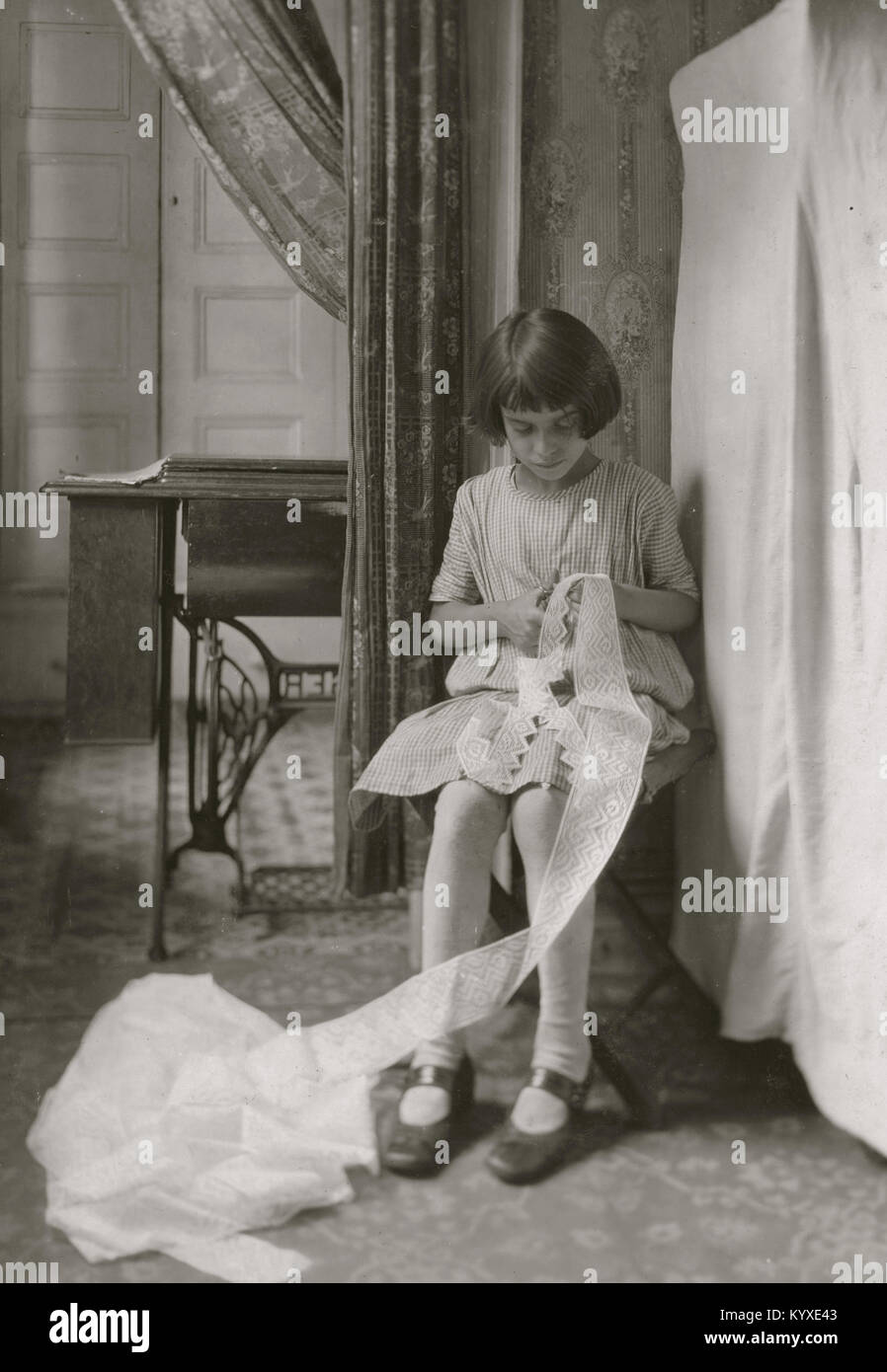 Young Girl cuts lace in here tenement apartment Stock Photo