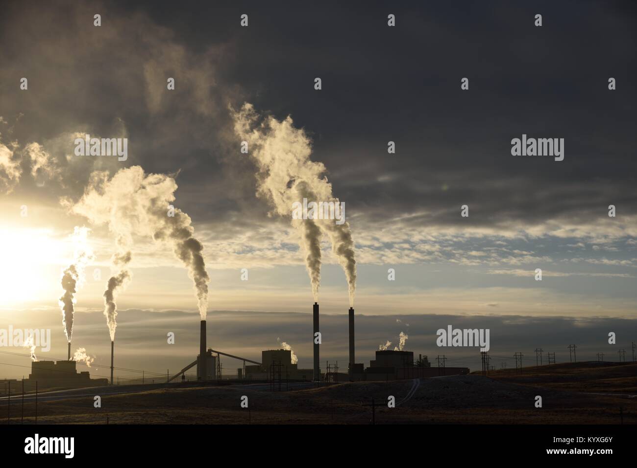 Carbon emissions rising from the smoke stacks of an industrial coal-fired power plant at sunset Stock Photo