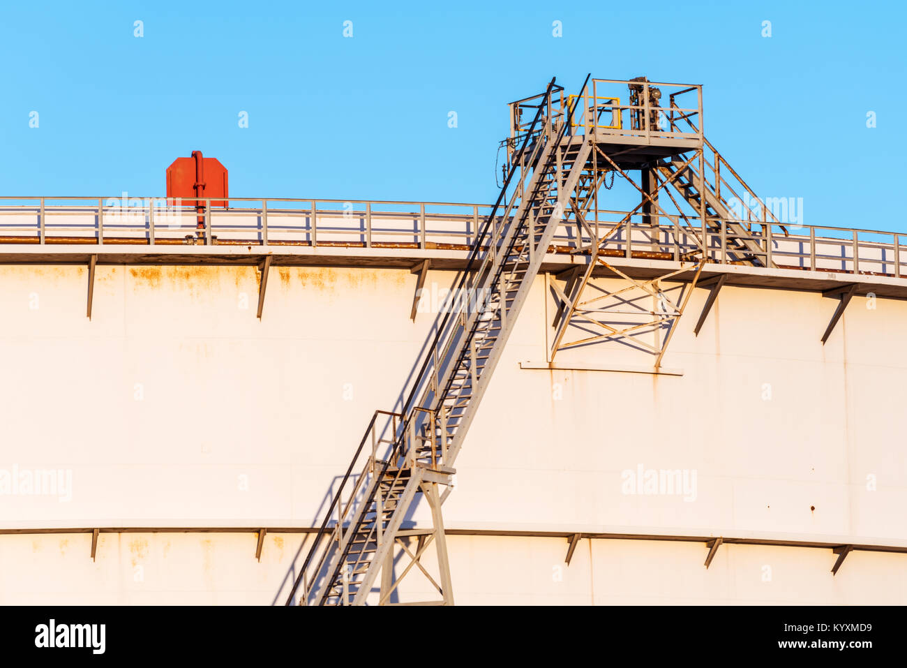 Detail of a staircase alongside a large oil storage tank on a sunny late afternoon in the harbour of Rotterdam. Stock Photo