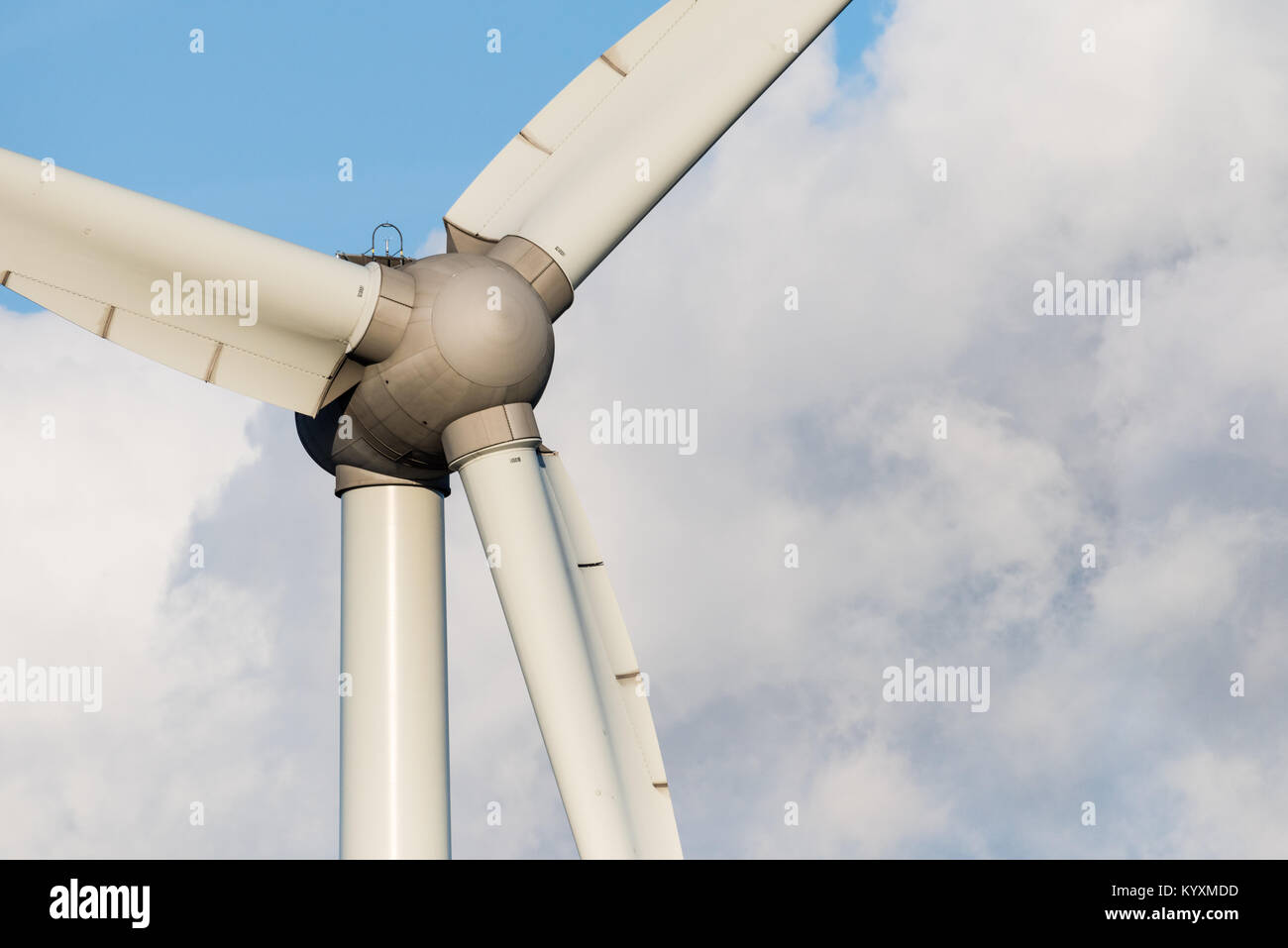 Closeup of a wind turbine on a sunny day against a blue clouded sky and ...
