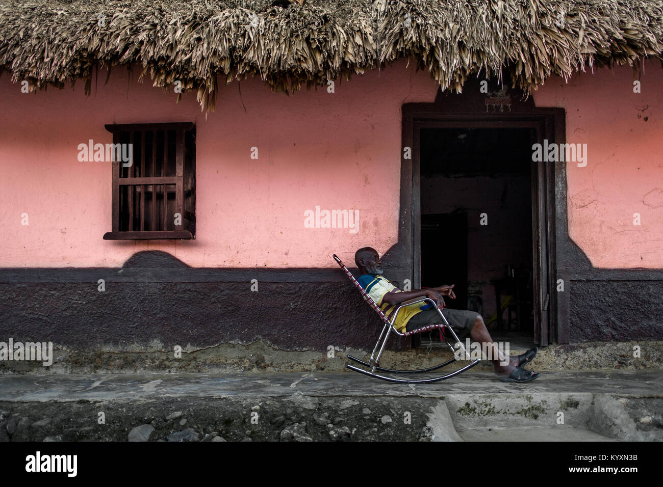 An old Colombian man sits in a rocking chair in front of his house in San Basilio de Palenque, a village in the Caribbean region of Colombia. Stock Photo
