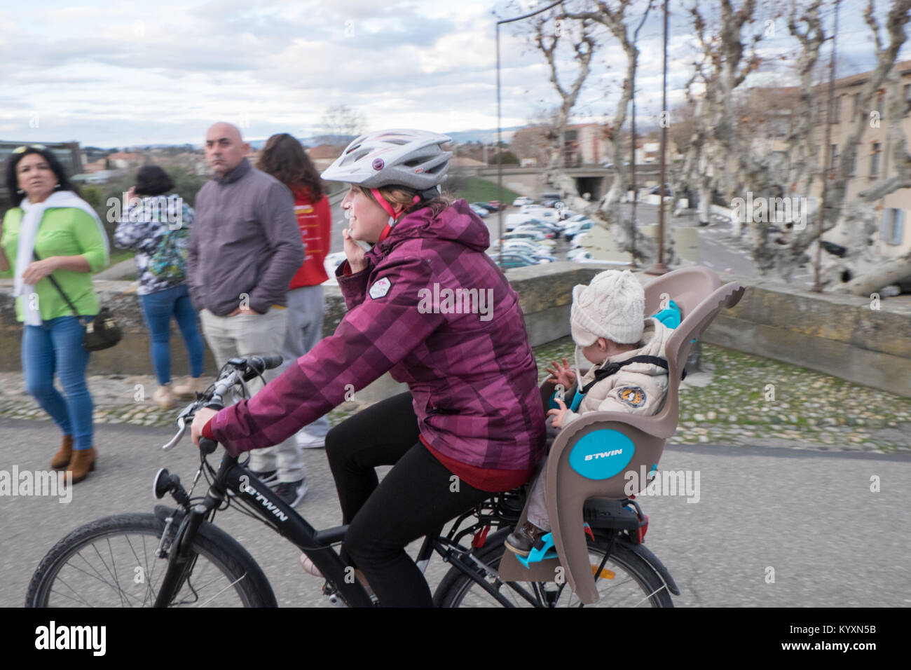 woman,multi,tasking,checking,her,mobile,phone,while,riding,bicycle,bike,with,child,on,board,crossing,Le Pont Vieux,The Old Bridge,Carcassonne,France, Stock Photo