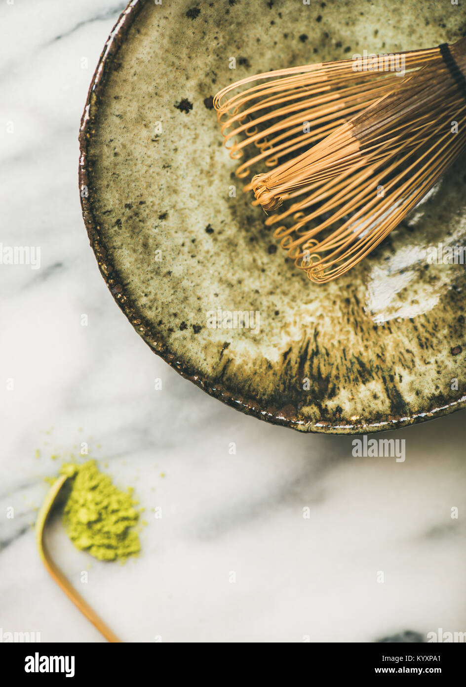 Flat-lay of Japanese tools for brewing matcha tea. Matcha powder in tin can, Chashaku spoon, Chasen bamboo whisk, Chawan bowl over grey background, to Stock Photo