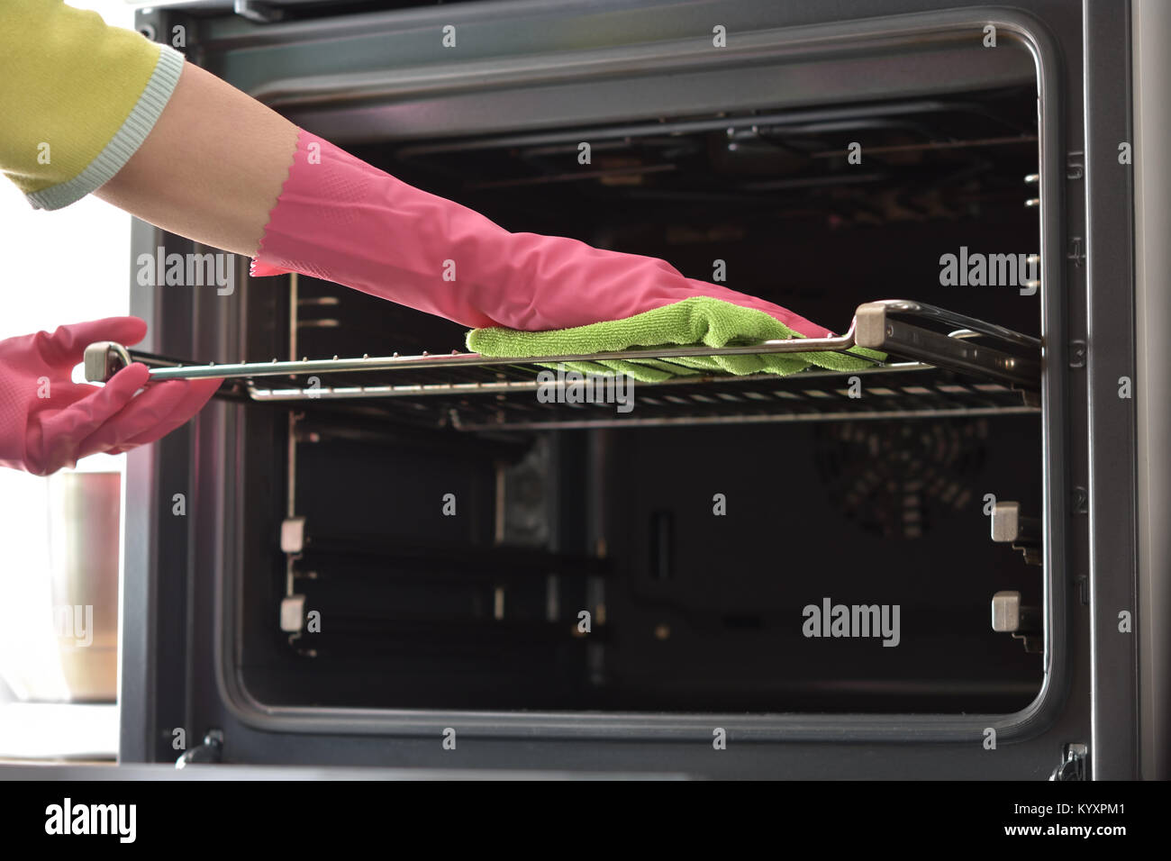 Cleaning the oven. Woman's hand in household cleaning gloves cleans oven inside. Clean oven in kitchen. Stock Photo