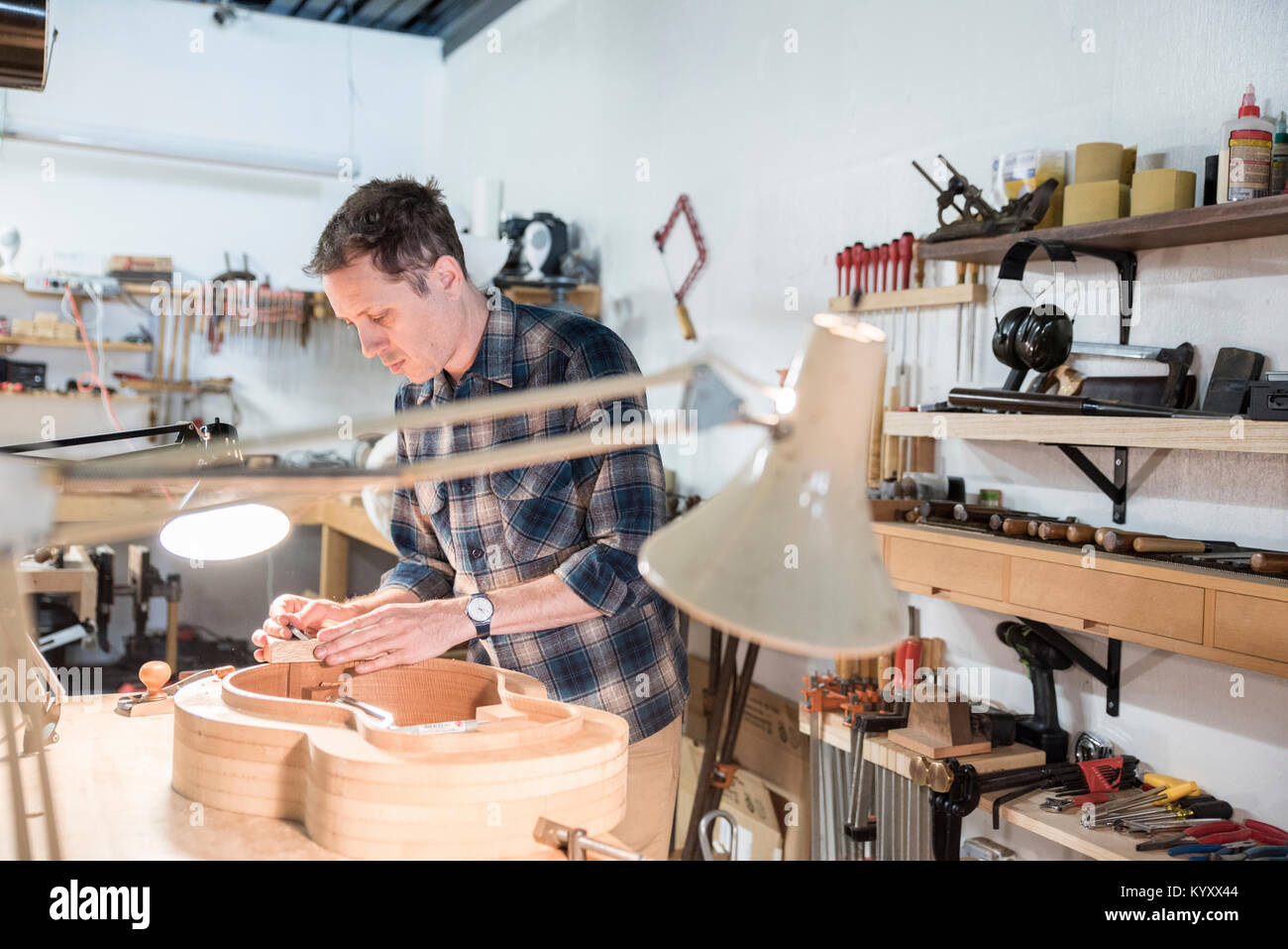 Worker making guitar while standing in workshop Stock Photo