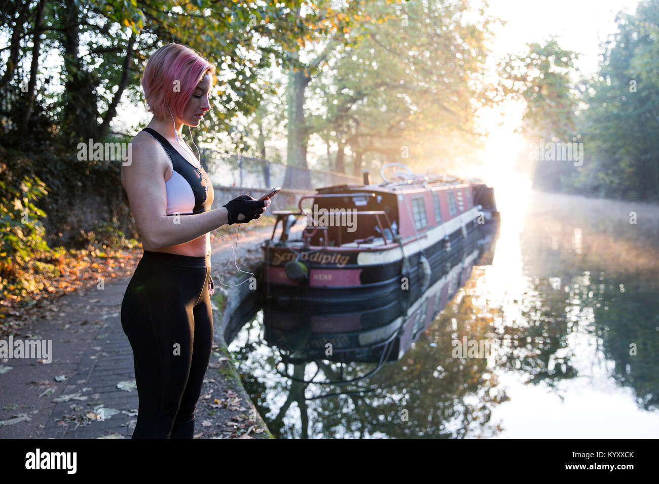 Woman wearing sports clothing while using smart phone by lake at park Stock Photo