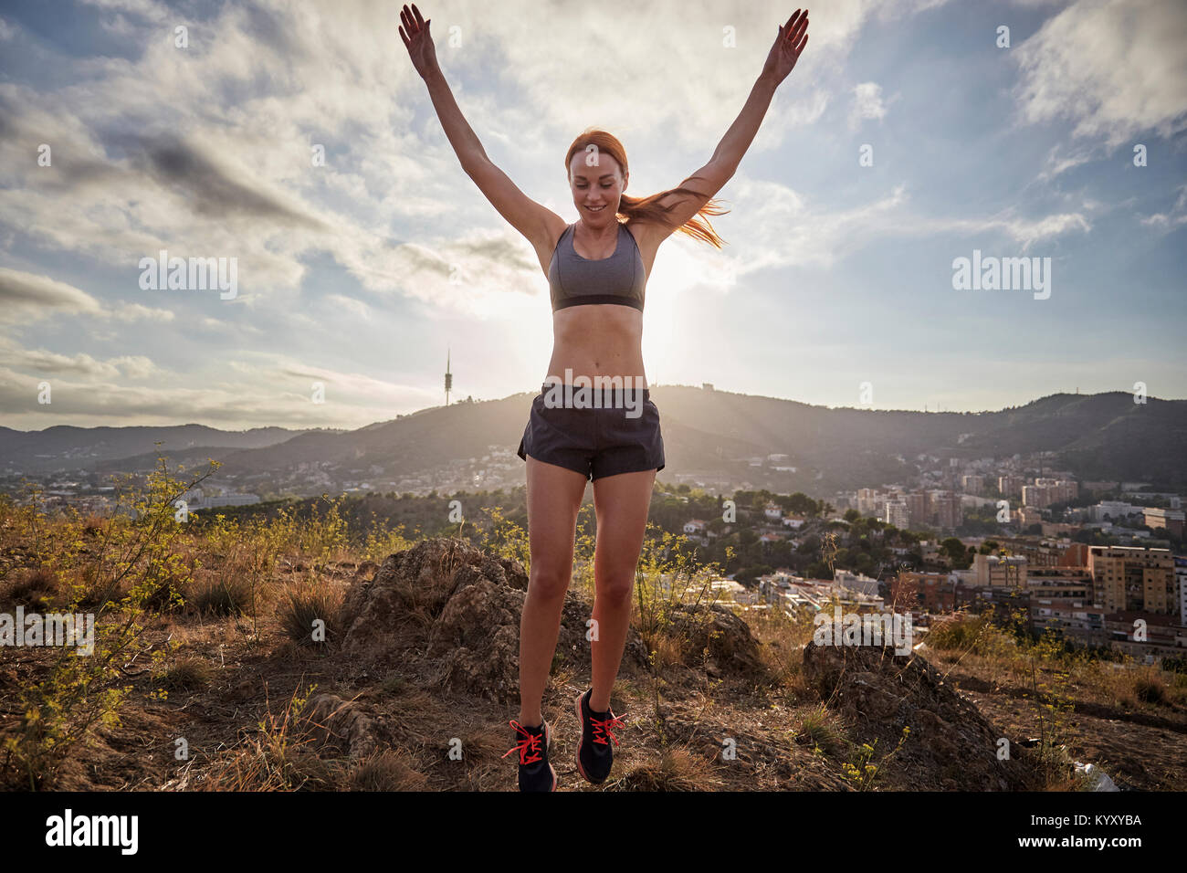 Woman with arms raised standing tiptoes while exercising against