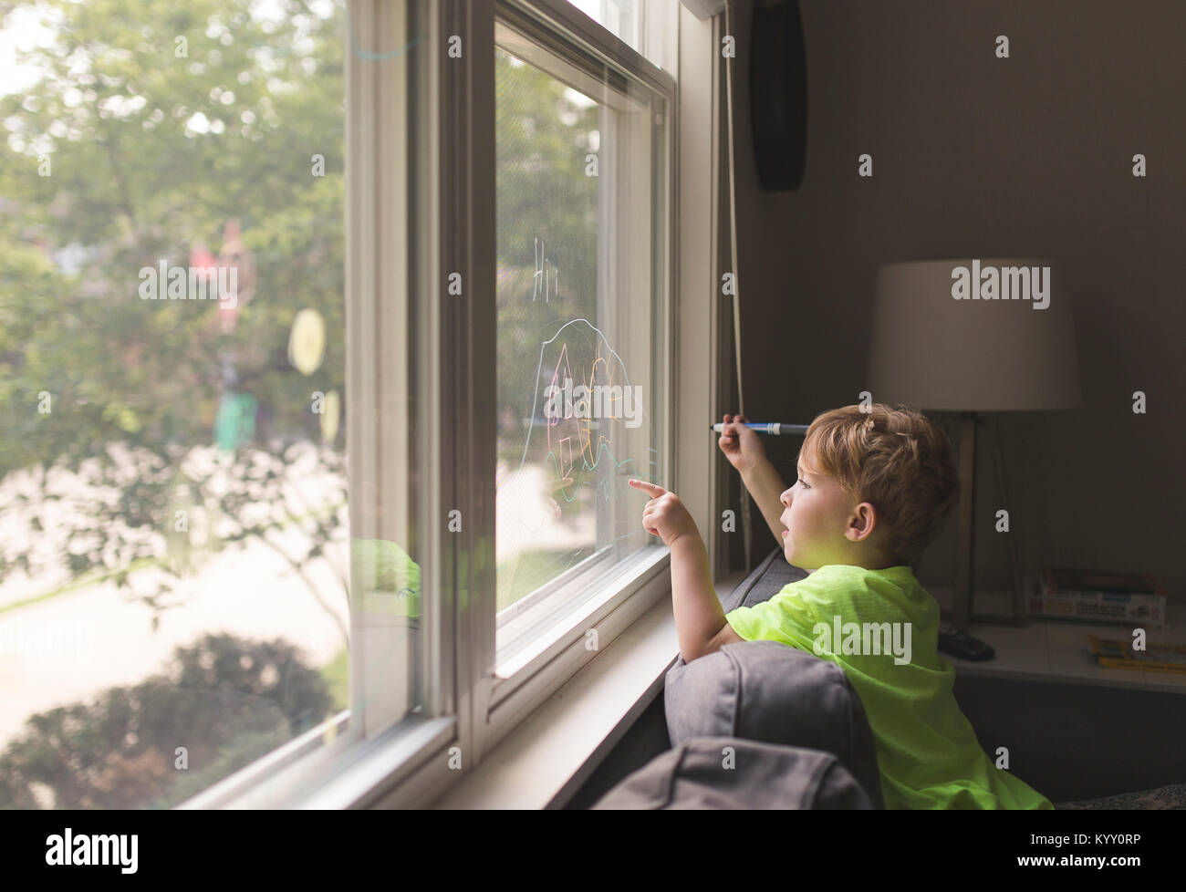 Side view of boy writing on window at home Stock Photo