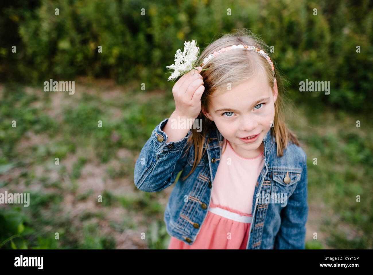 High angle portrait of girl wearing flower while standing on field at park Stock Photo