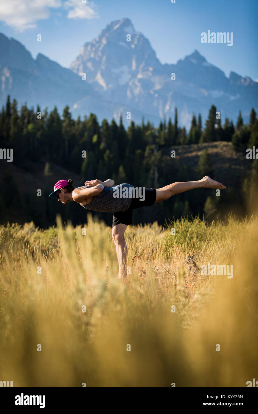 Side view of man standing on one leg while practicing yoga on field at Bridger-Teton National Forest Stock Photo