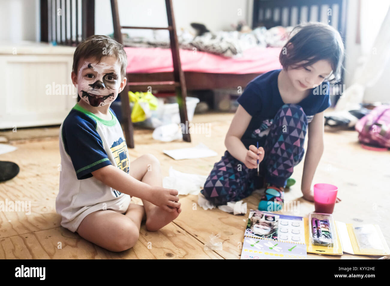 Portrait of boy with spooky face paint sitting by sister on floor at home Stock Photo