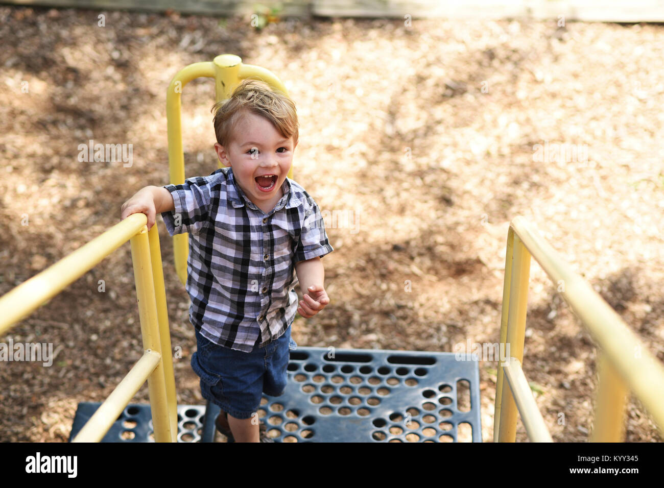 High angle view of playful boy shouting while standing on outdoor play equipment at playground Stock Photo