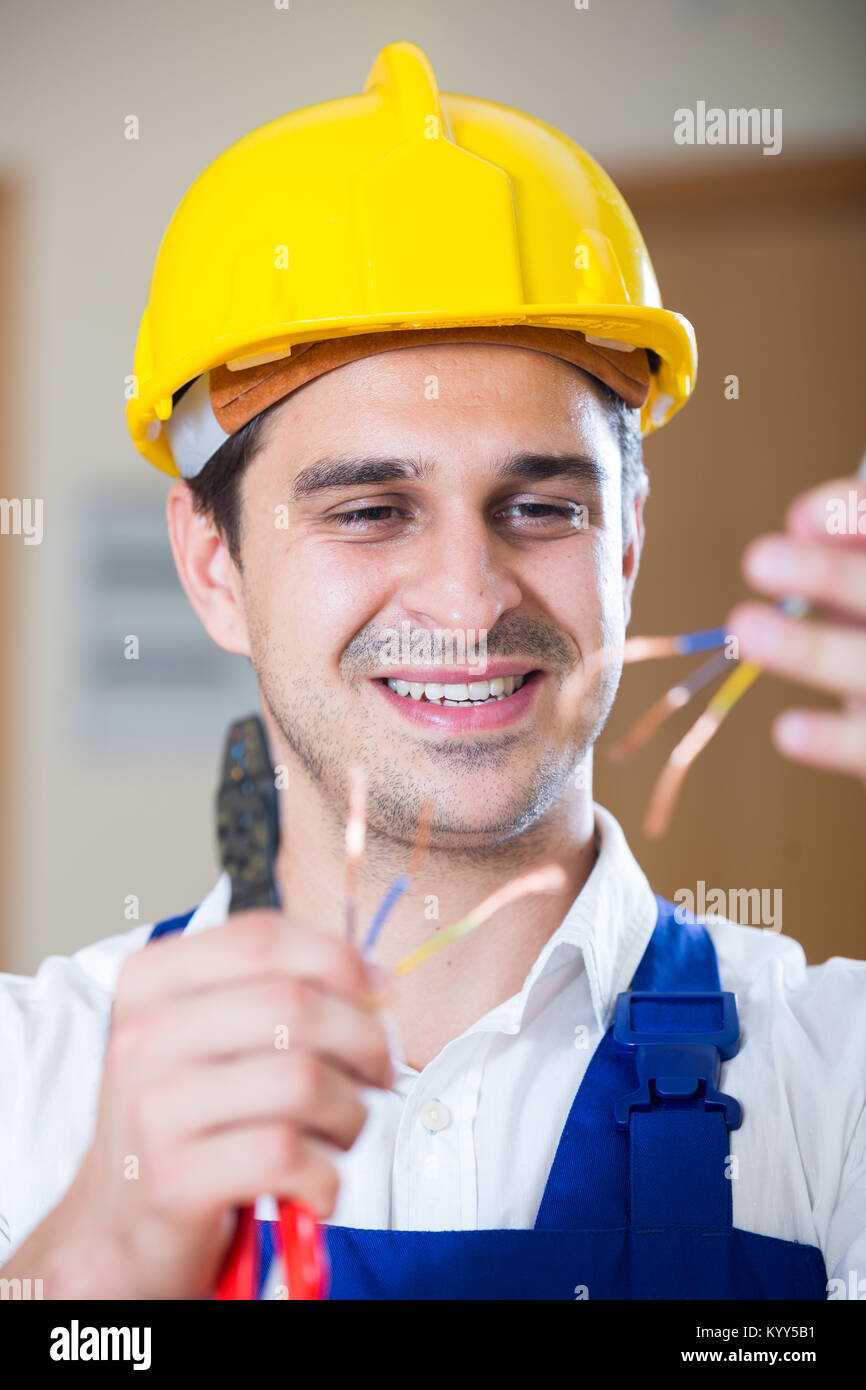Professional electrician working with wires at client home Stock Photo