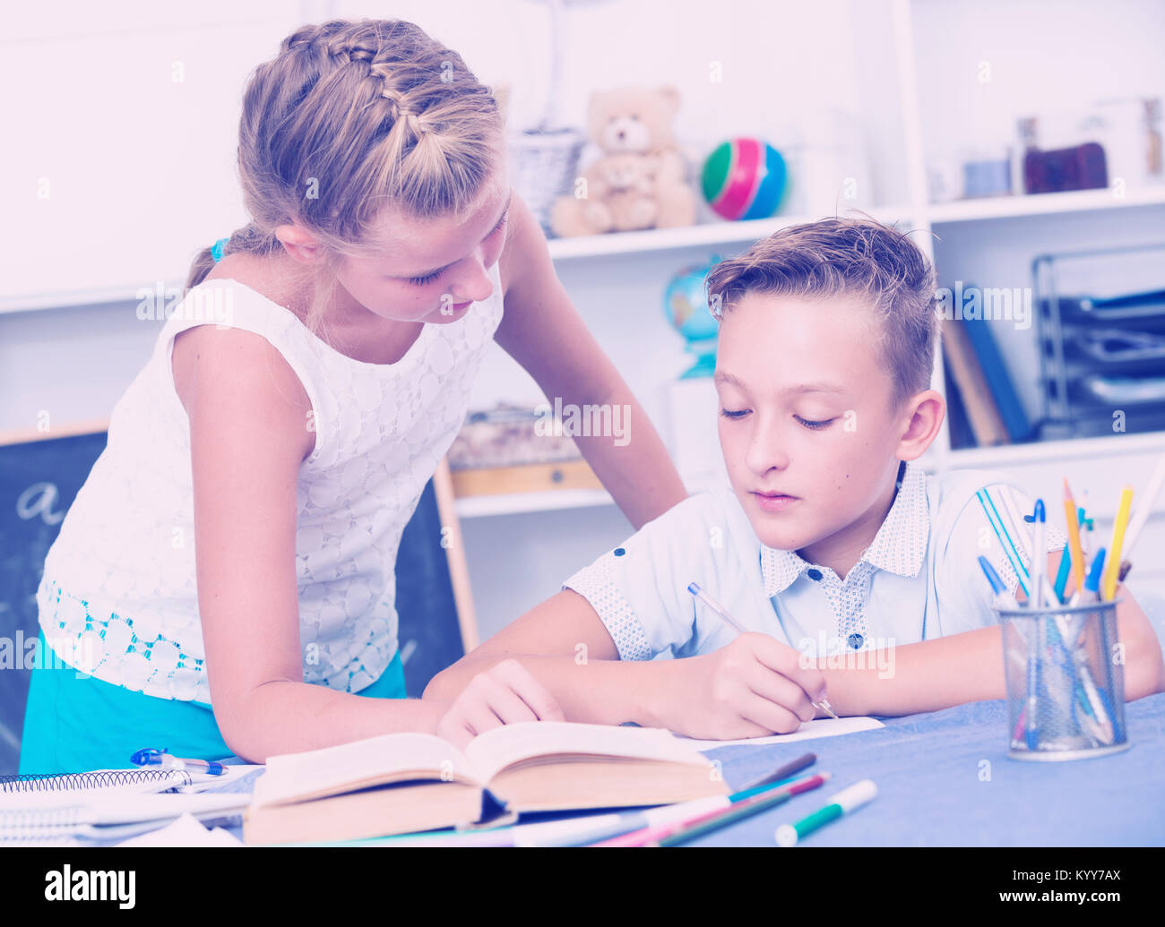 Girl is explaining to boy how to solve homework at home. Stock Photo