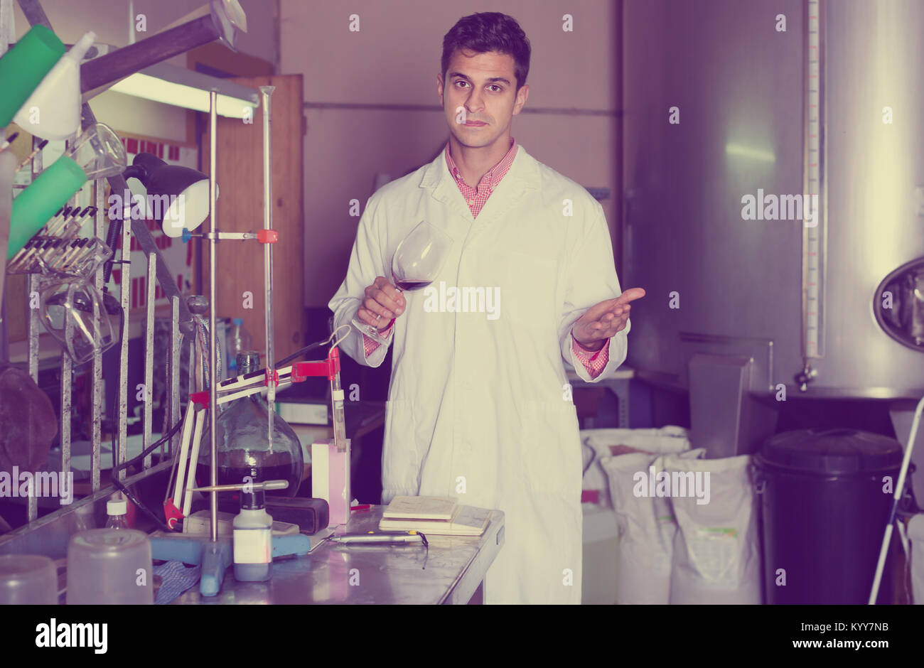 Attentive male laboratory technician working with wine in cellar Stock