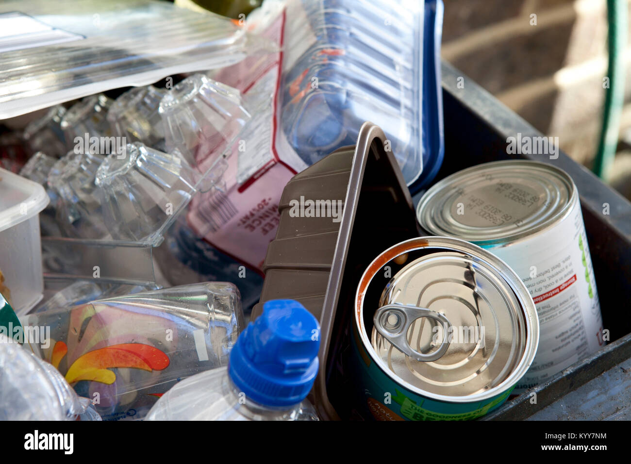 Wheelie bin full of domestic recycling waste, glass bottles, tin cans and plastic bottles, plastic waste, Recycling. Stock Photo
