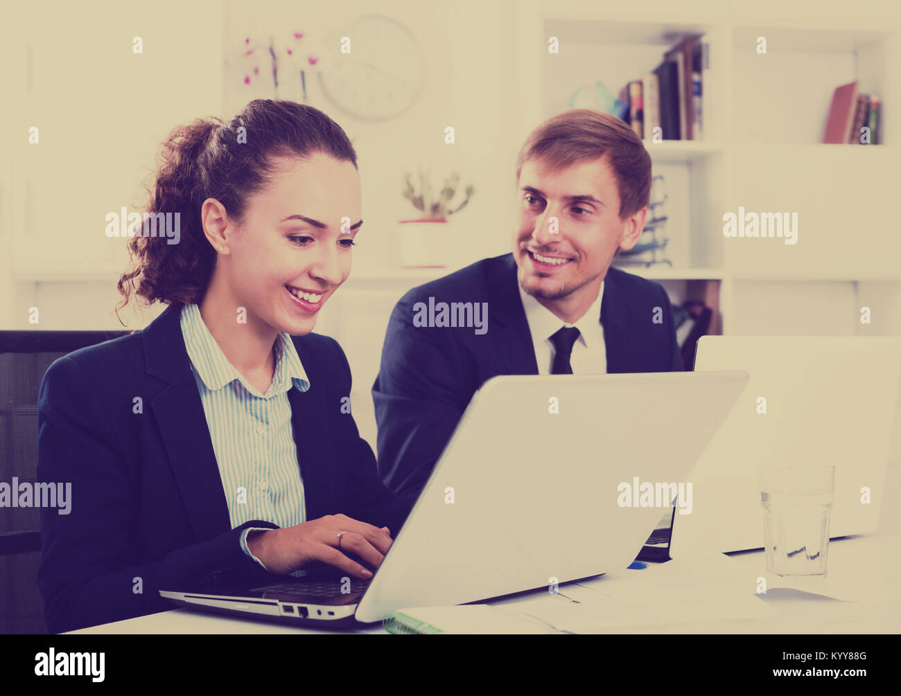 Man and cheerful woman coworkers sitting and working on computers in ...