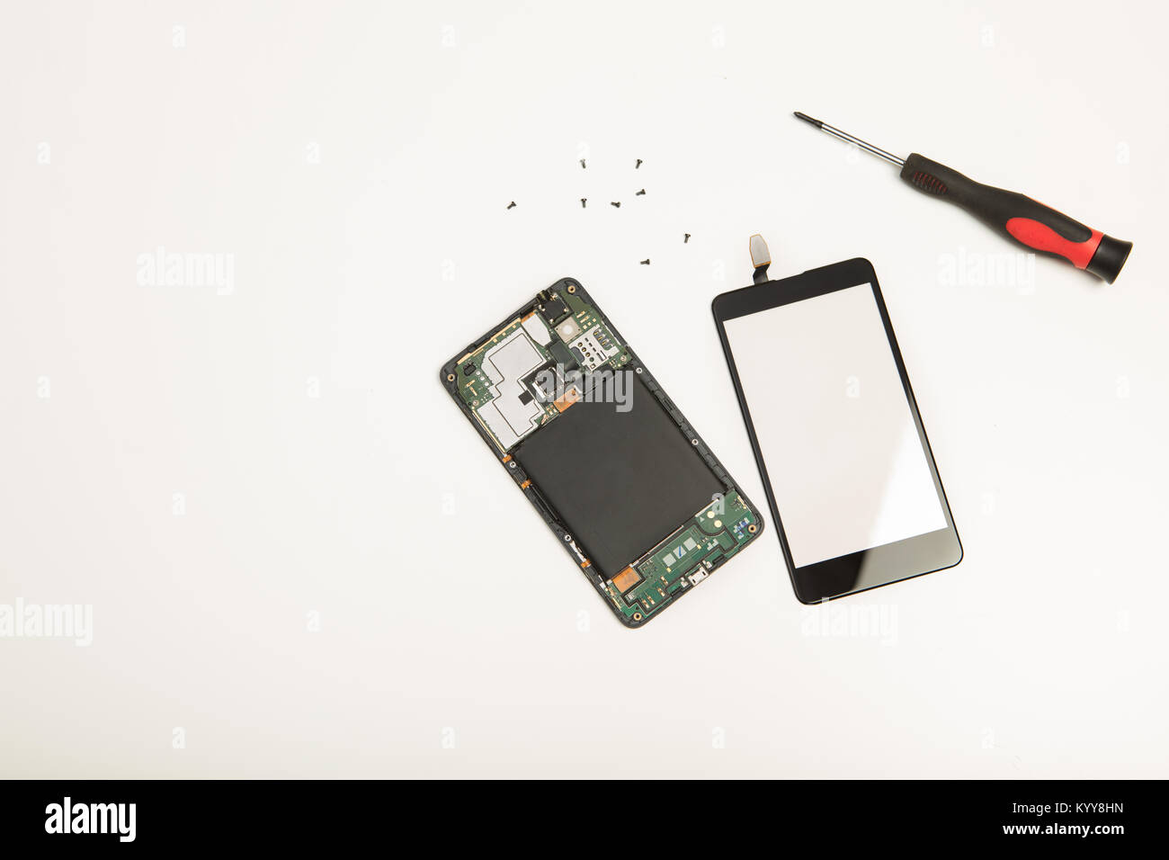 Opened smartphone showing the components, screen and circuitry together with a screwdriver and tiny screws on a white background with copy space Stock Photo