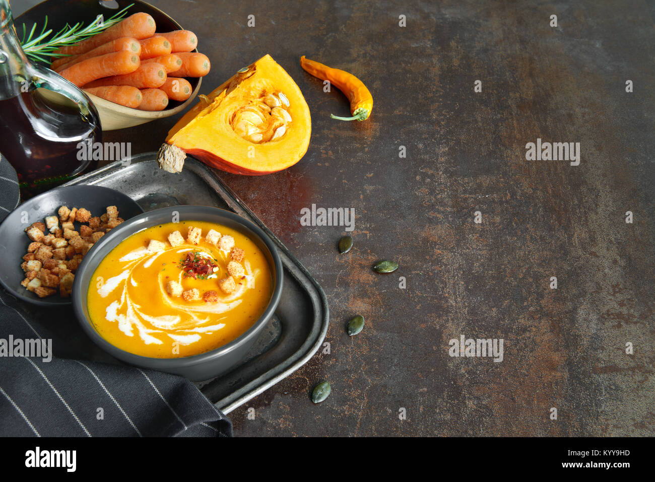 Spicy pumpkin soup wit ginger, onion and garlic, served with croutons, cream and dried chili. Side view, dark background, text space. Stock Photo