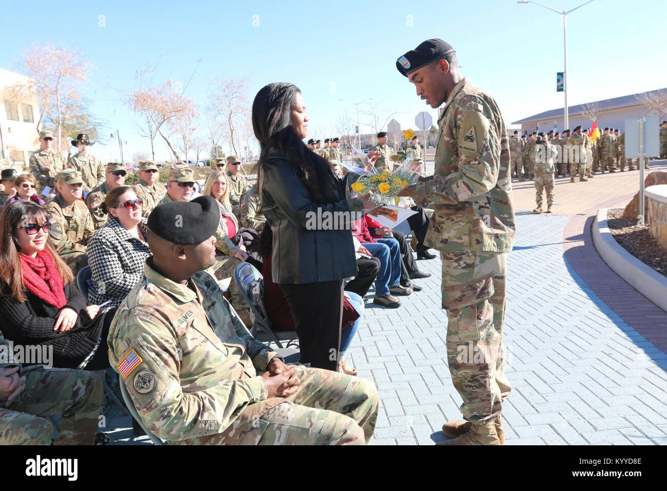 Diana Oliver, wife of Command Sgt. Maj. Michael Oliver, incoming senior enlisted adviser for 3rd Armored Brigade Combat Team, 1st Armored Division, receives yellow roses from Spc. William R. Ford, human resources specialist with Headquarters and Headquarters Company, 3 ABCT, 1 AD, during the brigade's change of responsibility ceremony January 11, 2018 to welcome her to the brigade. (U.S. Army Stock Photo
