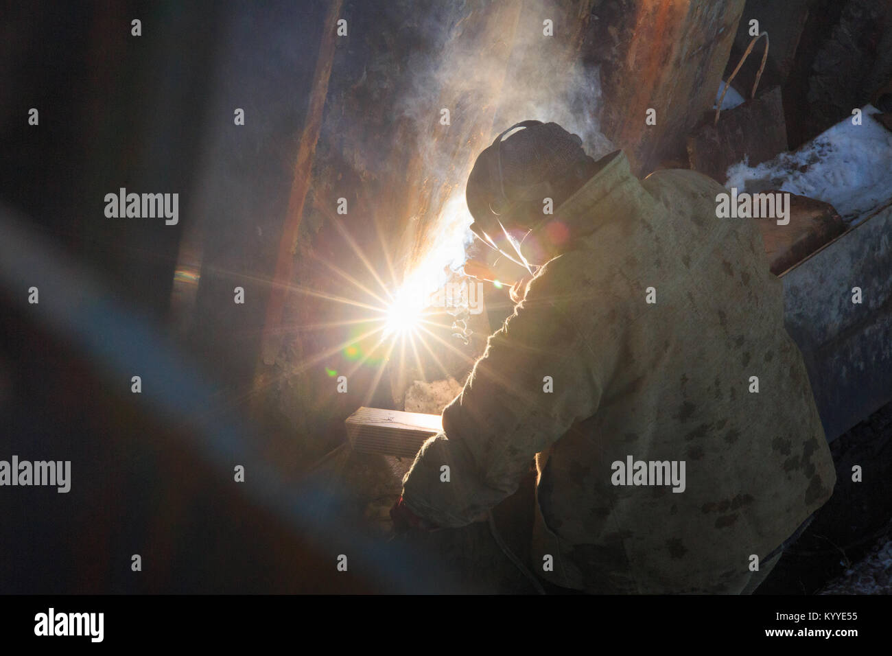 Welder from the back, in backlight from electric welding. Stock Photo