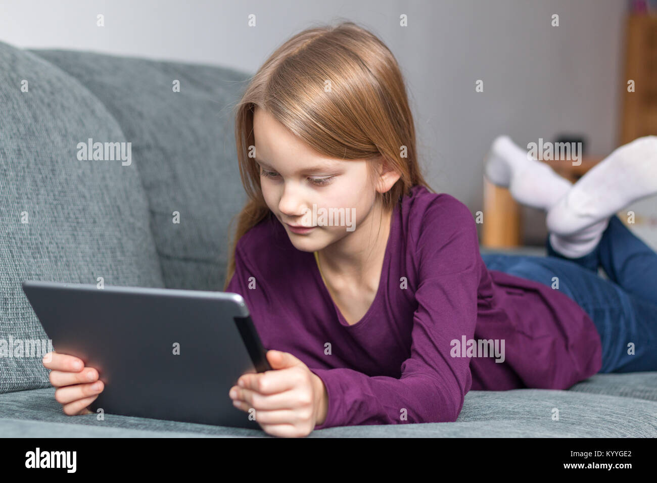 A girl lies on the sofa with a tablet PC in her hands Stock Photo - Alamy