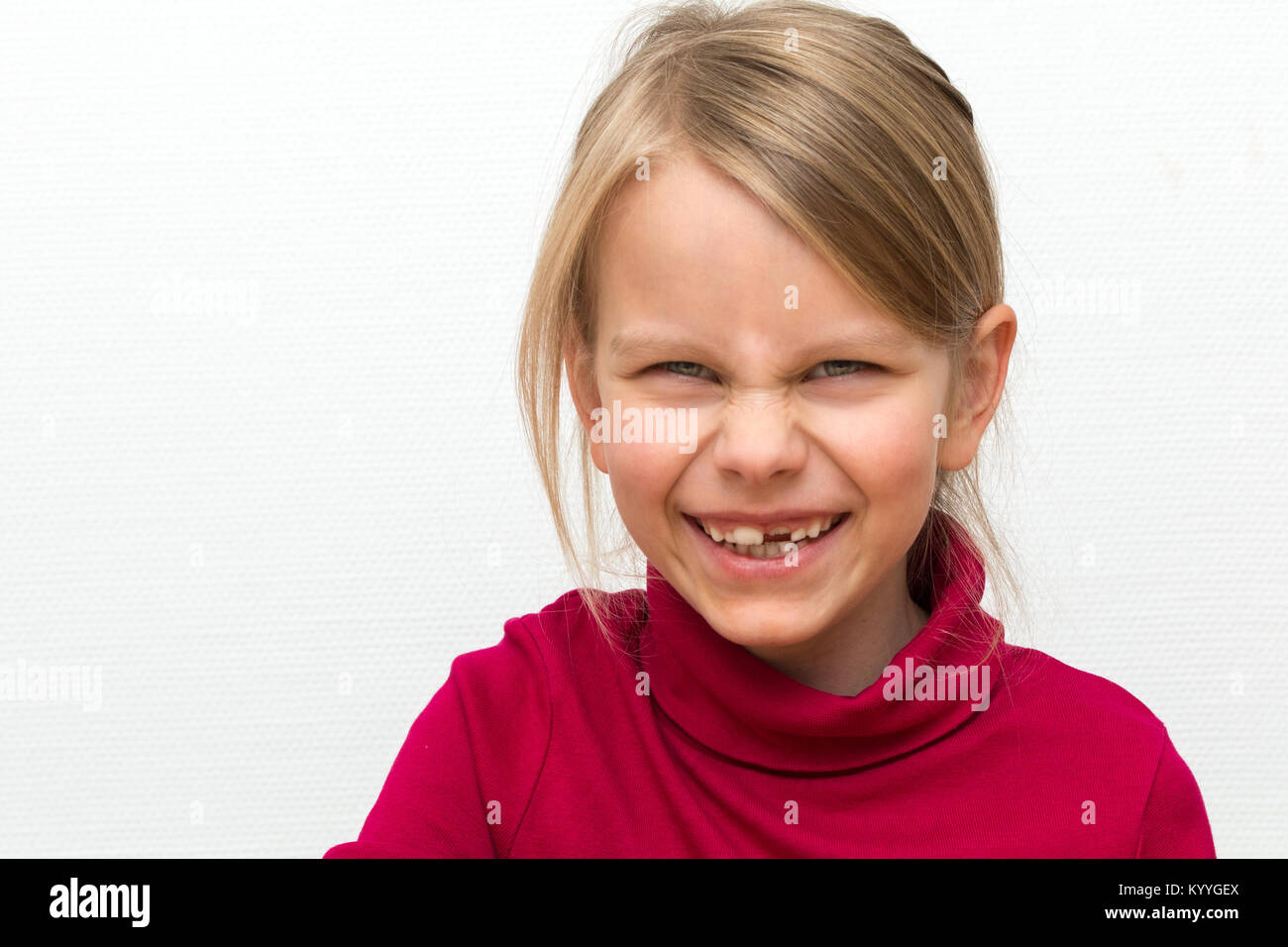 Portrait of a 6 years old blond girl. It wears a red turtleneck and has a beaming laugh Stock Photo