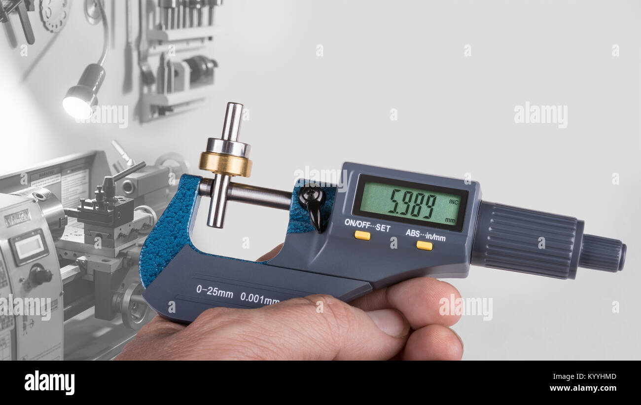 Detail of human hand with digital micrometer. Gauging of a metal part by the accurate measuring tool on black and white background with a lathe. Stock Photo