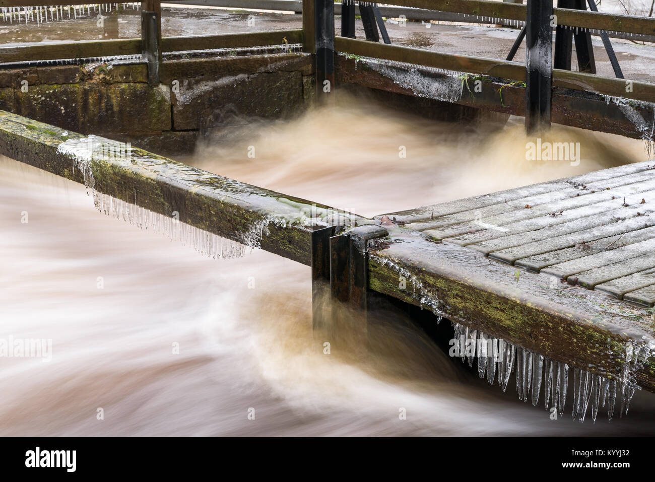 Ice and icicles forming on beams and railings along a violent river. Stock Photo