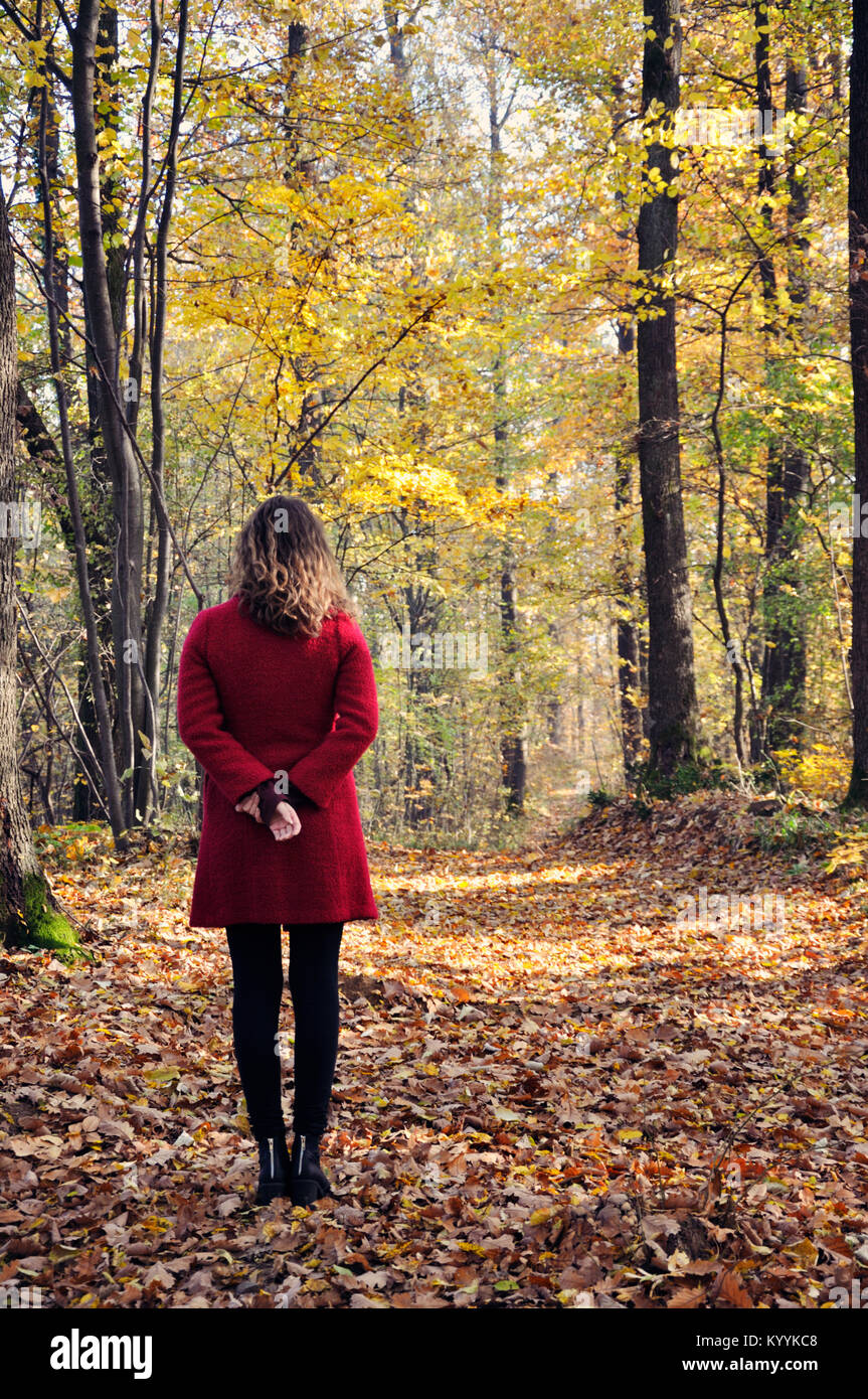Woman standing on path alone in forest Stock Photo