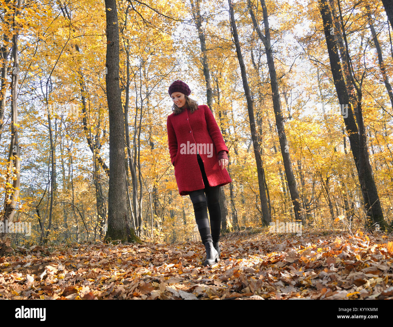 Young woman in red coat walking in forest Stock Photo