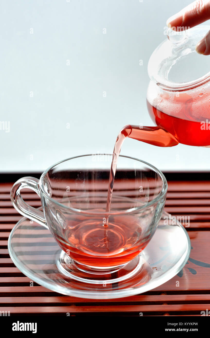 Pouring tea into a clear glass cafe style cup from teapot Stock Photo