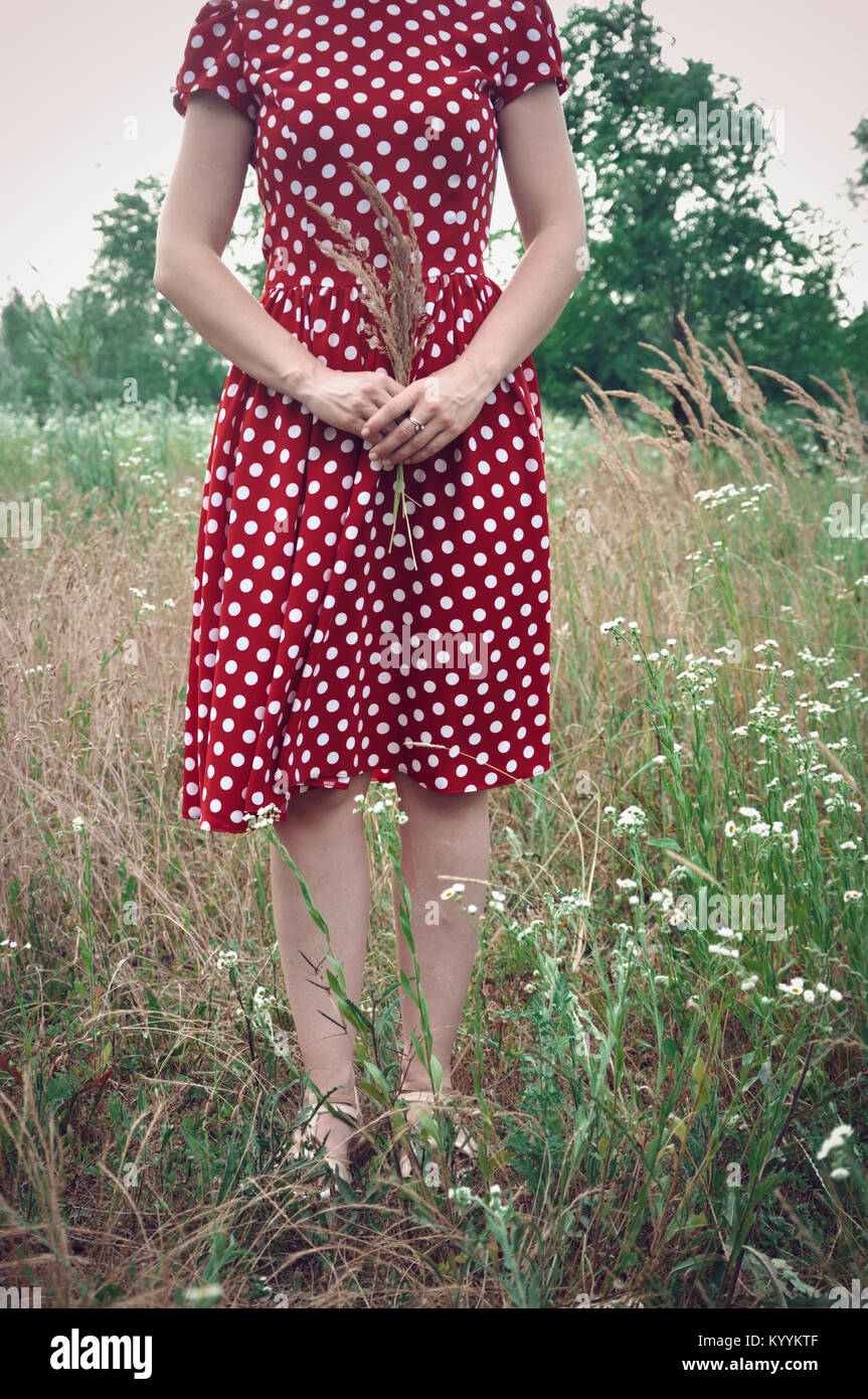 Woman in red dress standing in field Stock Photo