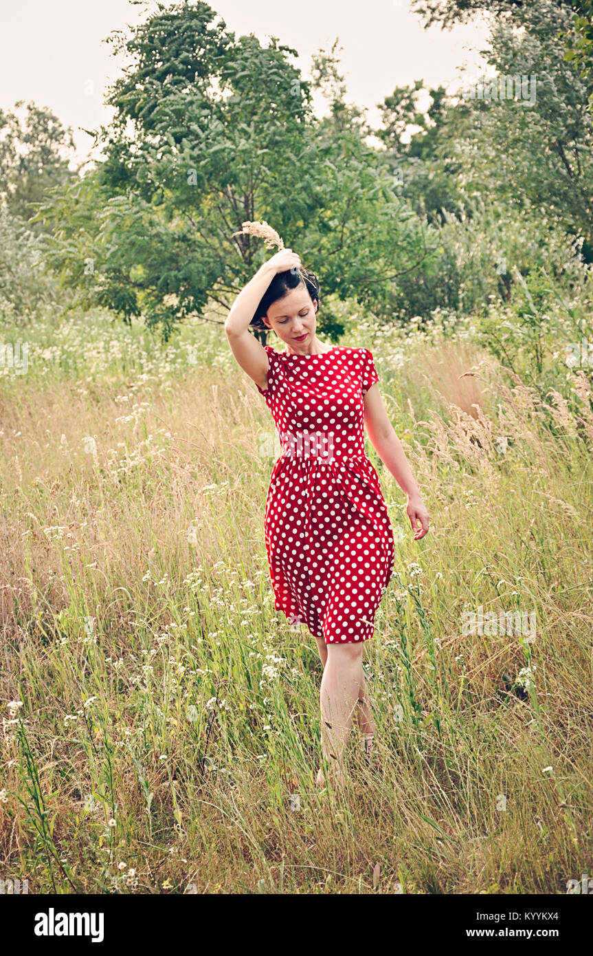 Woman in summer dress walking in field Stock Photo