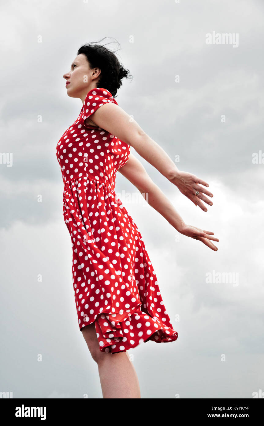 Woman in red polka dot dress standing outdoors Stock Photo - Alamy
