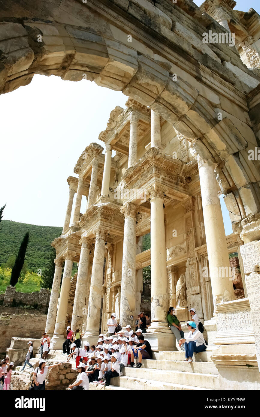 Selçuk, Turkey - April 21, 2008: View through an old arch to the ruins of the ancient Roman library of Celsus and tourists sitting on the steps in the Stock Photo