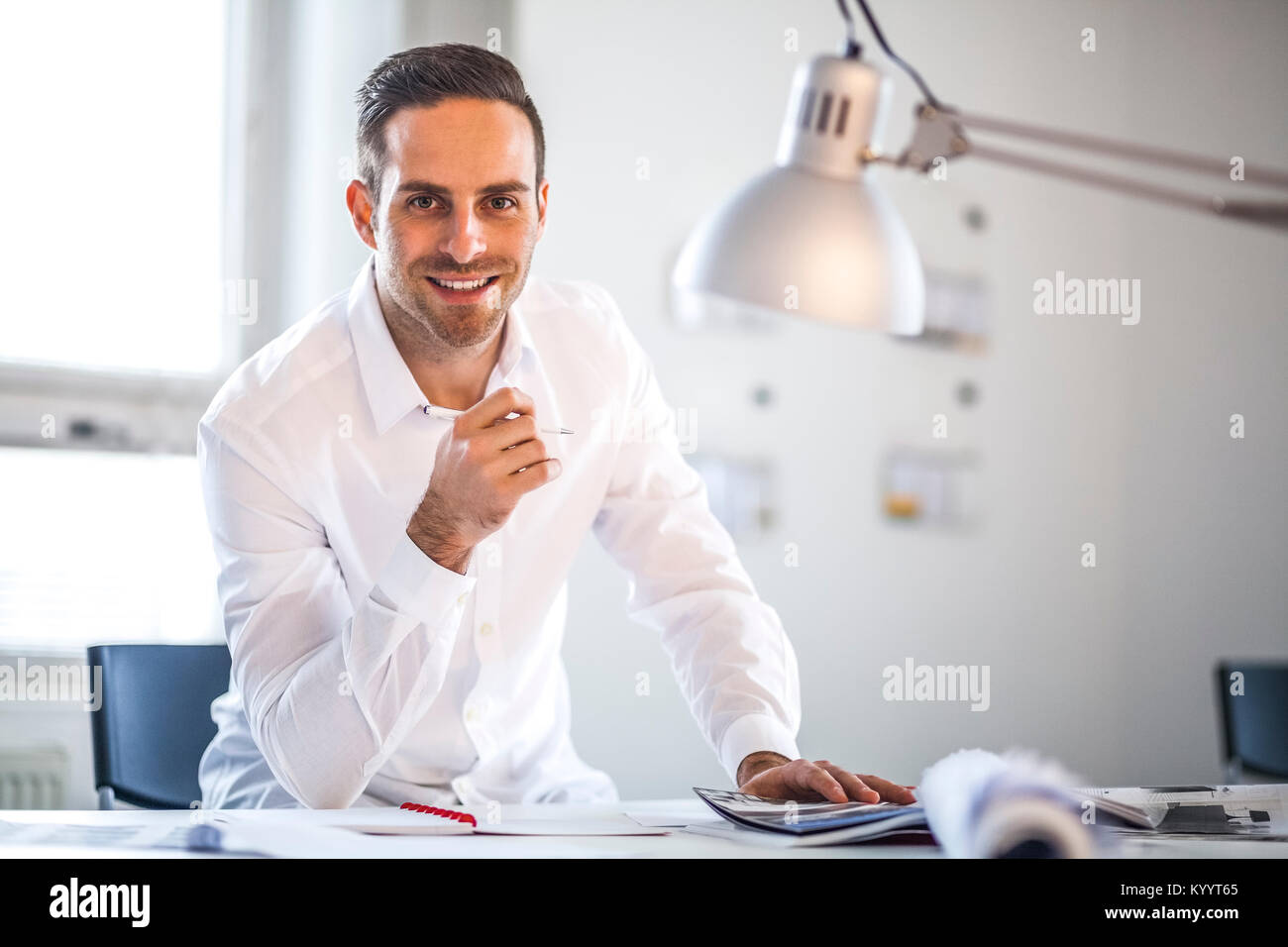 Portrait of businessman holding pen at desk in office Stock Photo - Alamy
