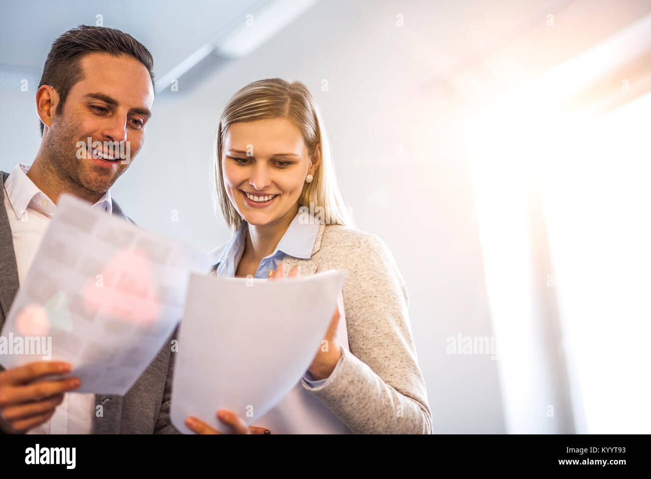 Smiling young business people reviewing documents in office Stock Photo ...