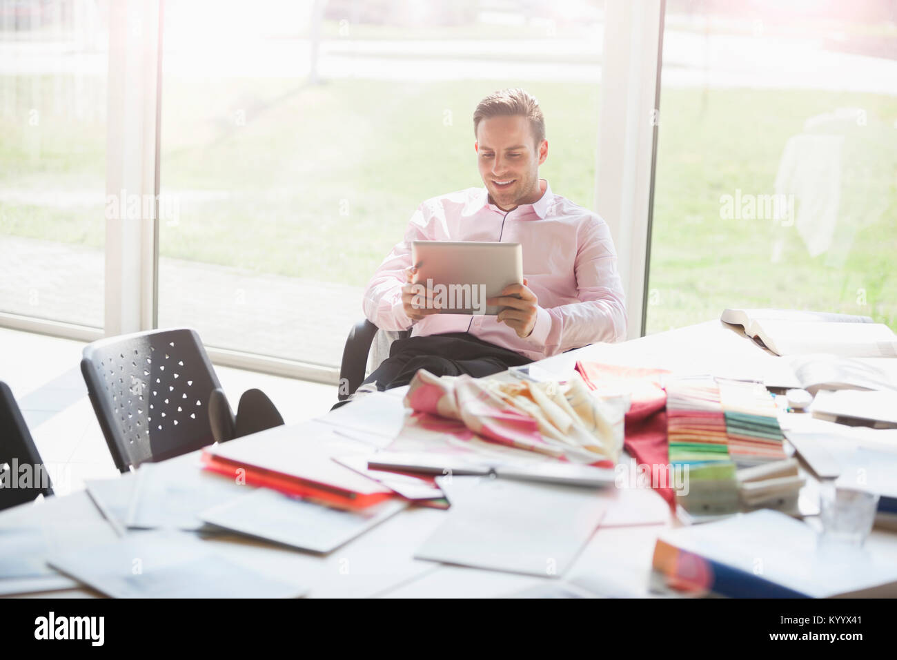 Happy young businessman using digital tablet at conference table in ...