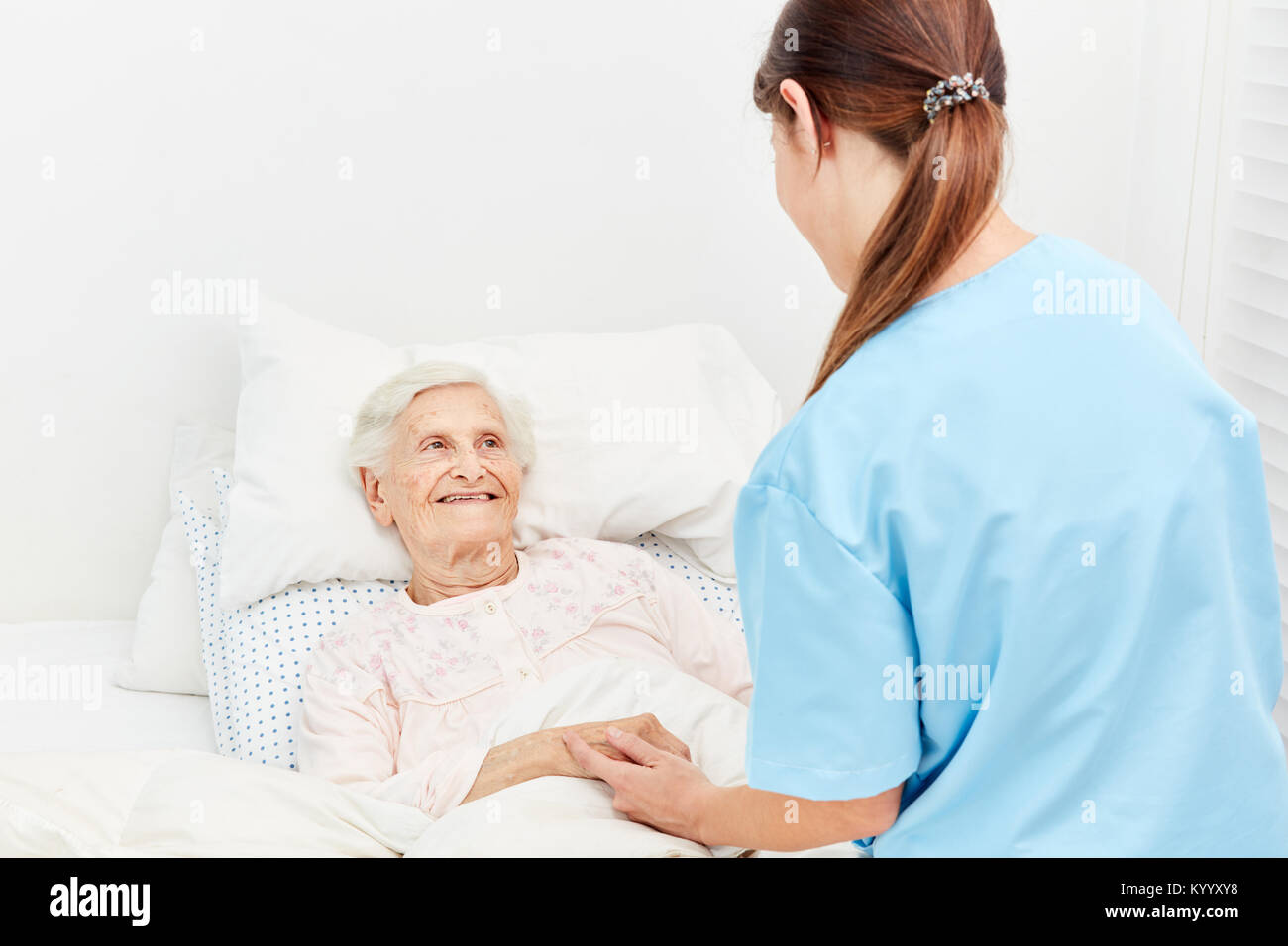 Old woman in hospice or nursing home is being comforted by a nurse Stock Photo