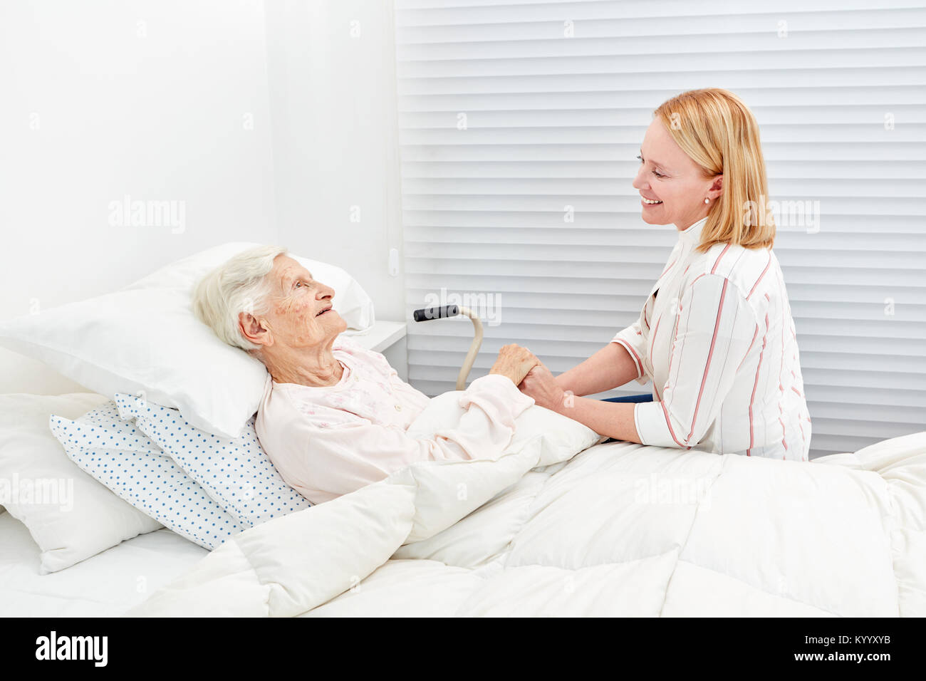 Woman makes a medical visit to bedridden senior citizen in the hospital Stock Photo