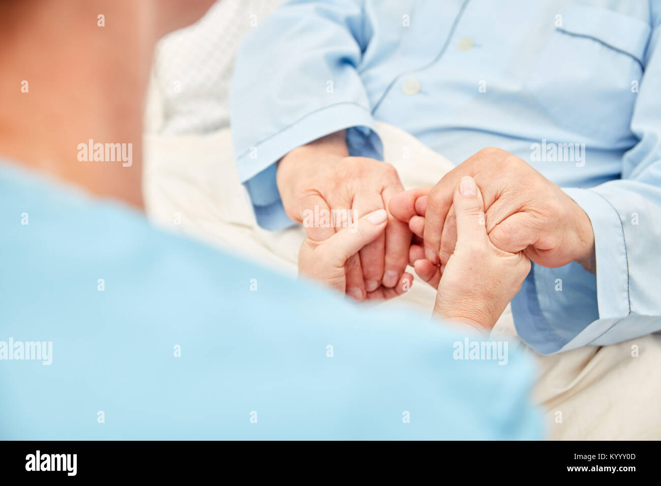Nursing lady holds the hands of a patient in the hospice as a terminal